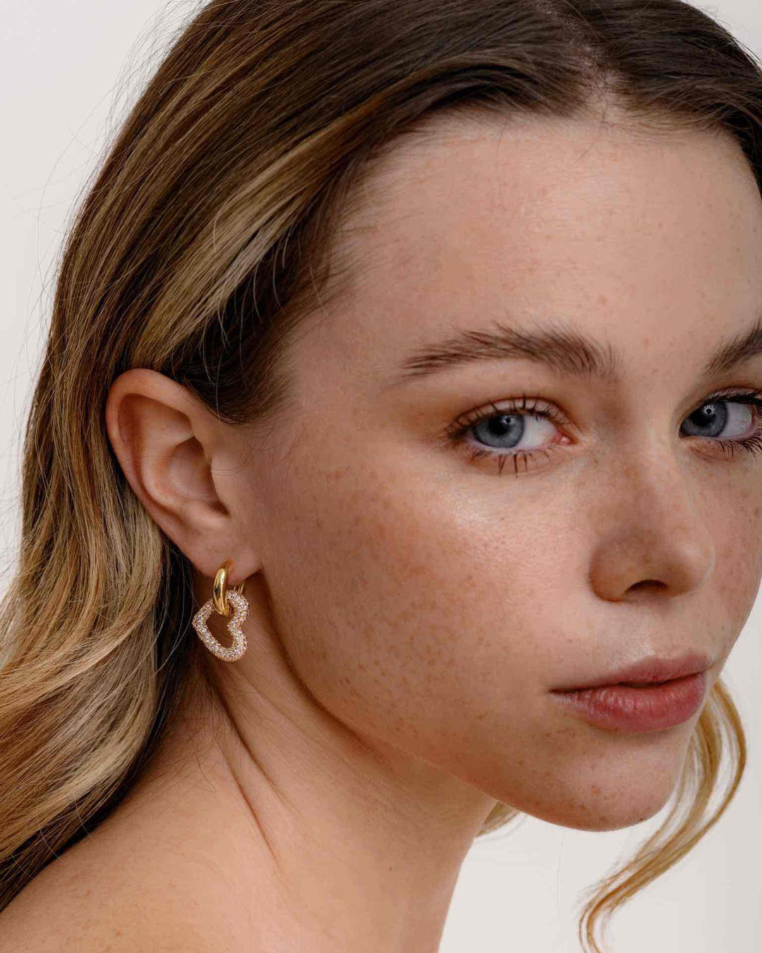 modella indossa orecchino a cerchio con pendente a cuore oro